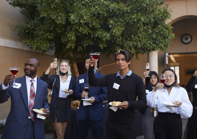 Students are dressed formally and attending an etiquette workshop. They lift their glasses for a toast.