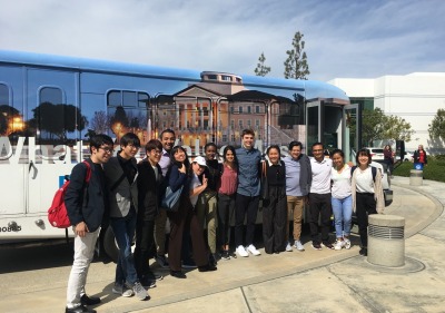 A group of students pose in front of the Soka University bus