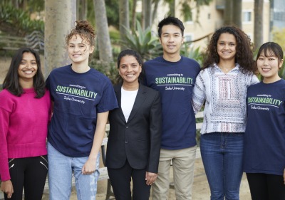 A picture with 5 students standing shoulder to shoulder, smiling at the camera