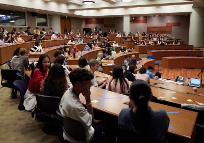 A large group of students sit in a lecture hall