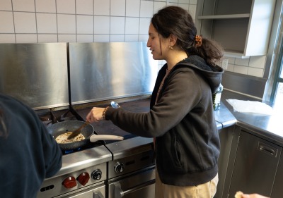 Mareva Dijoux ’26 cooks a tortilla in a skillet during the cooking portion of Esiobu’s Learning Cluster on Indigenous food systems.