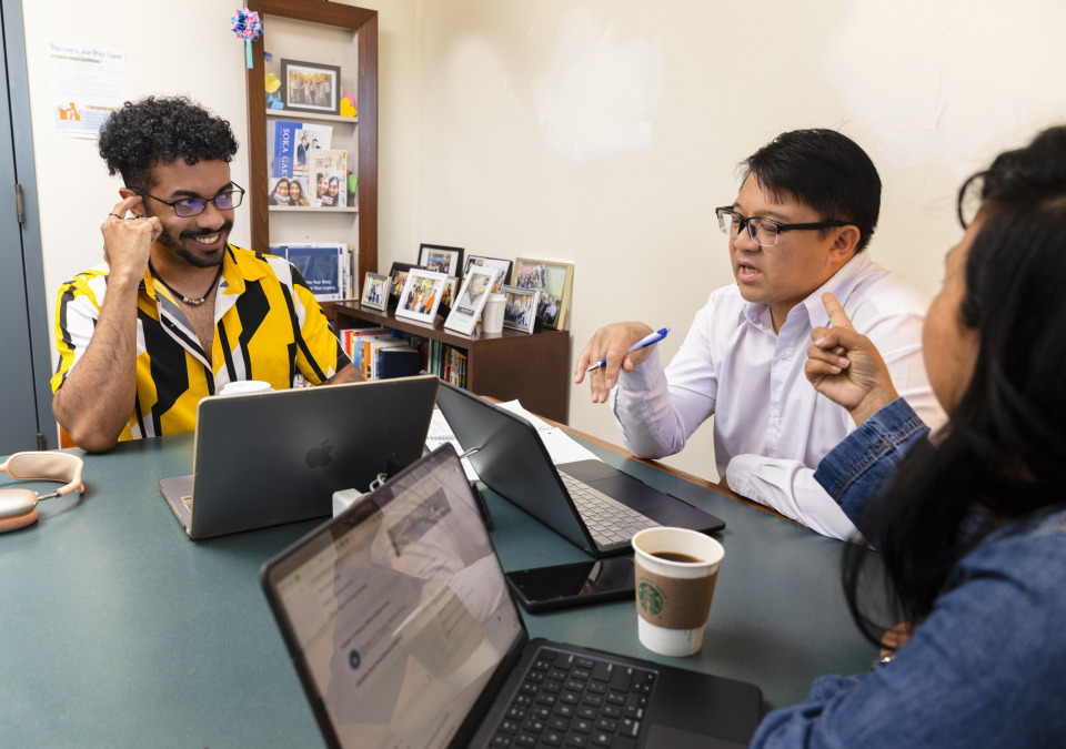 Three students work together on laptops