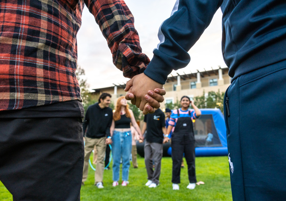 Two students hold hands during an activity at the Welcome Back event on SUA's campus.