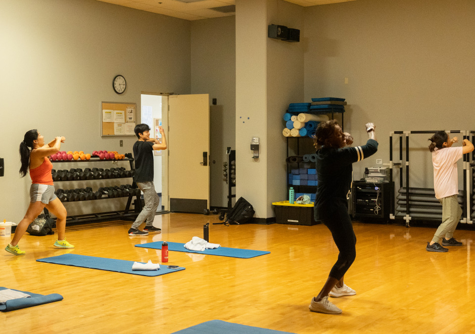 Four people wearing gym clothes participate in a group fitness class in SUA's Recreation Center