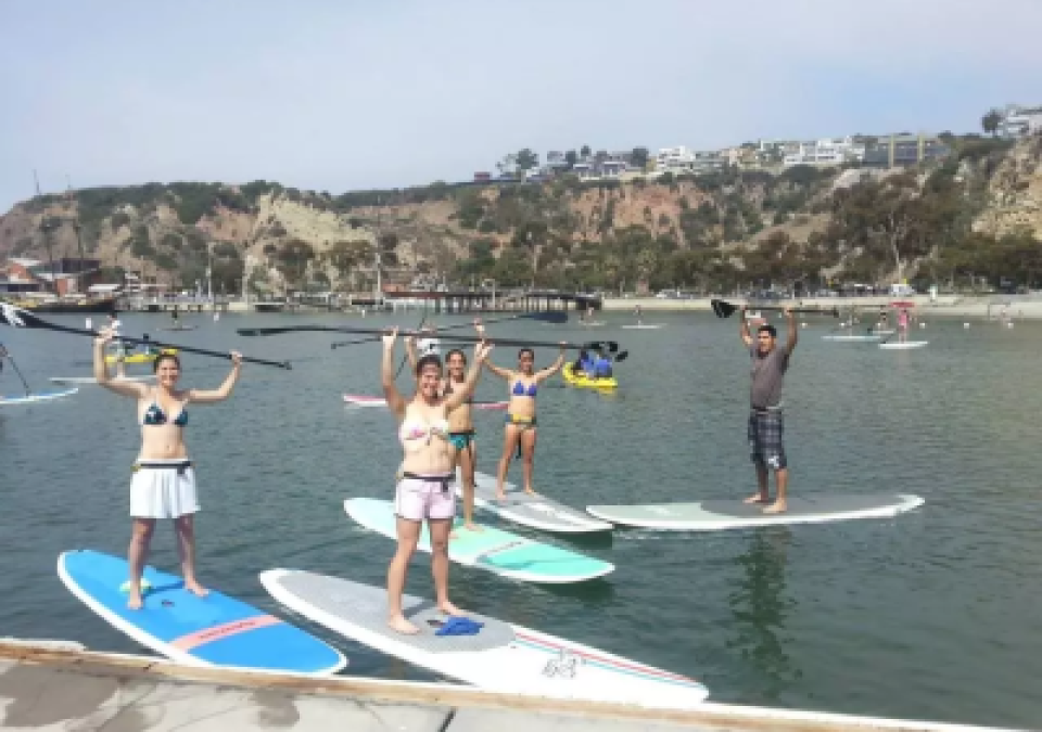 Students show off their paddles while paddleboarding during an outdoor adventure series.