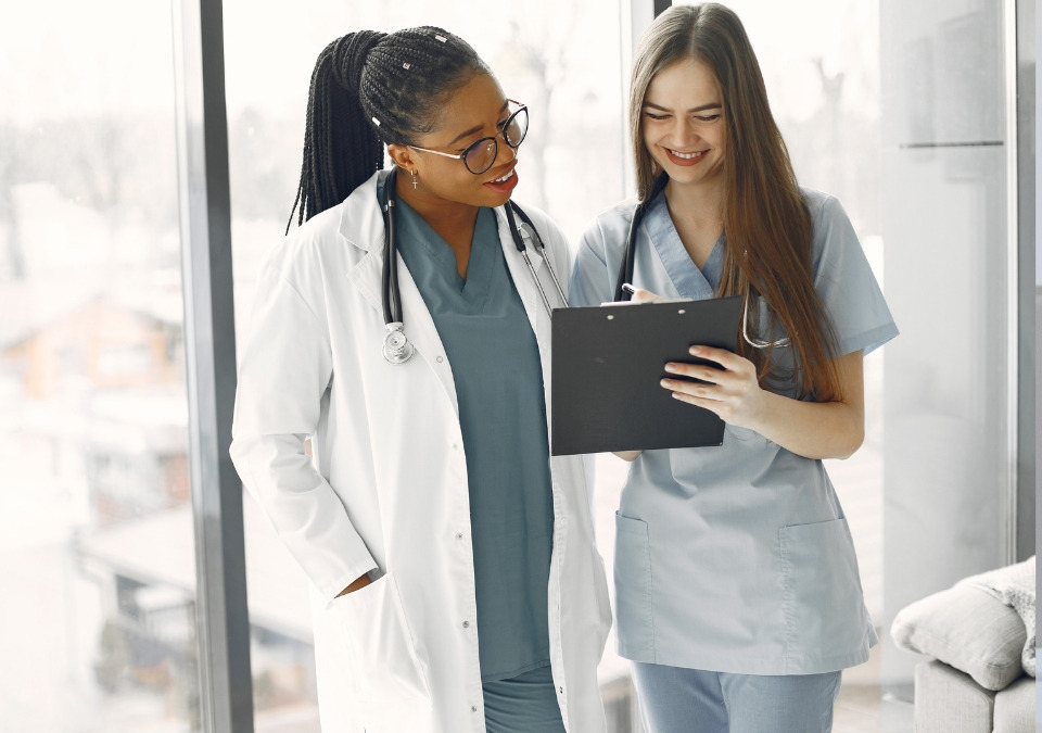 A doctor smiling and looking at the record that a woman is holding