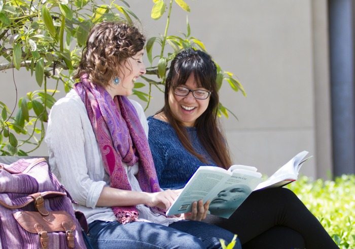 Students smiling and sharing a book