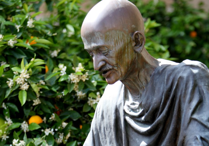 Statue of Gandhi in front of green trees