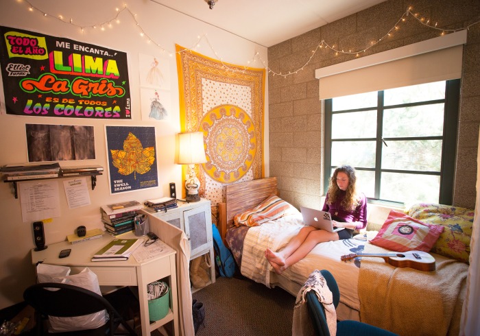 Girl sitting on bed in residence hall dorm room