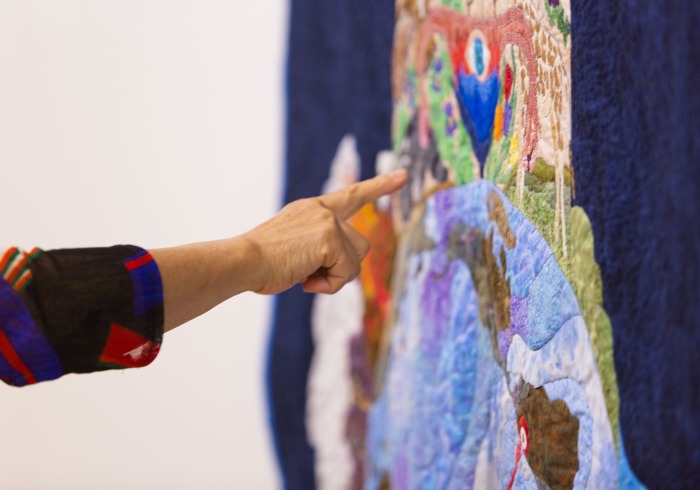 Close up image of a person gesturing to a quilt.