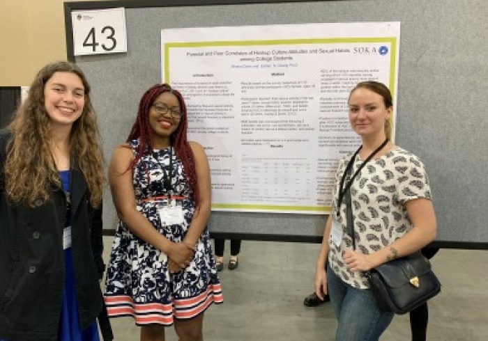 Students stand near presentation board