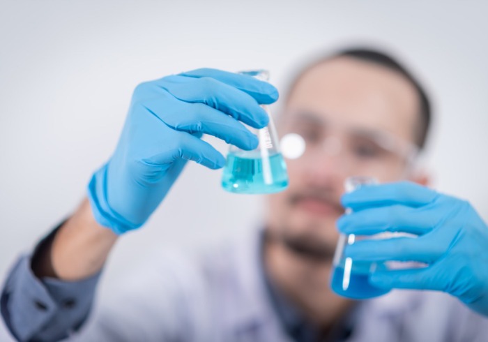 Person holding glass flasks in a lab