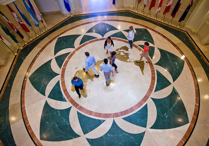 Students mingle on map of globe on the floor of Founders Hall