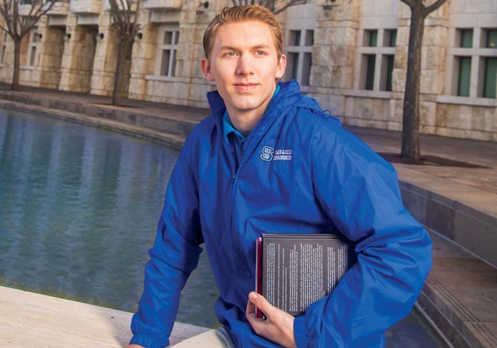 Student holding book in front of Peace Lake