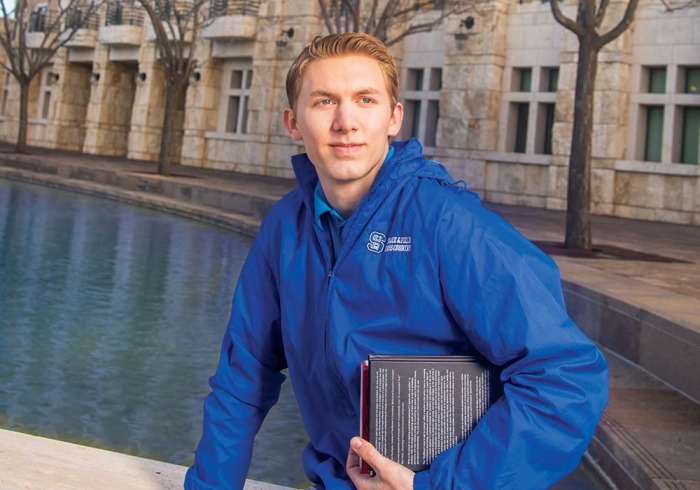 Student holding book in front of Peace Lake