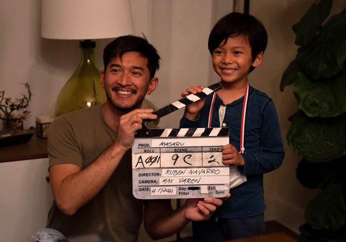 Michael Sasaki poses with a young male actor holding a clapperboard.