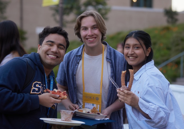 Three Soka students hold treats and smile for the camera