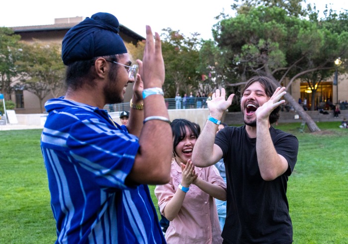 Three Soka students are clapping and high-fiving