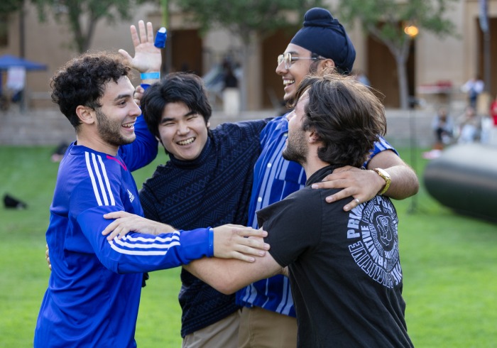 Four students celebrate and hug after winning a competition during Welcome Week