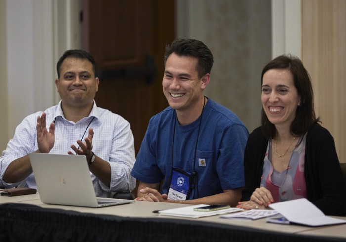 3 Conference attendees applaud and smile during discussions