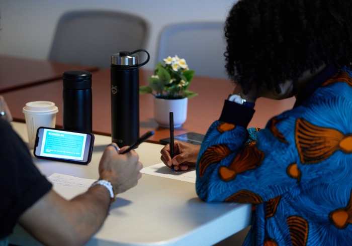 Two people share a table and are taking notes