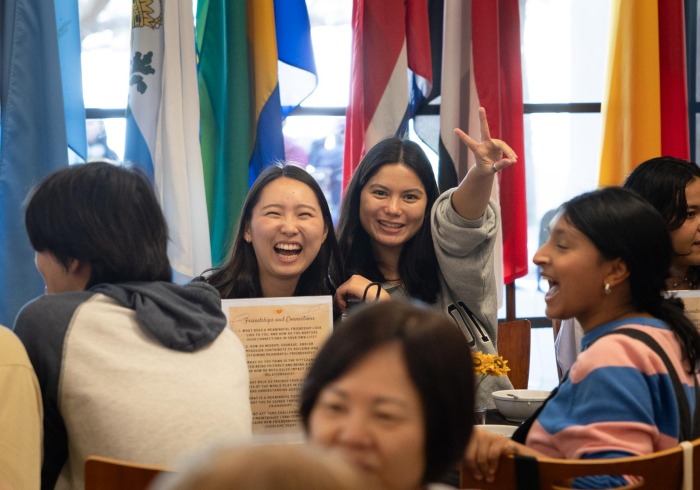 Two students smile at the camera amidst a crowd of people in the Bistro