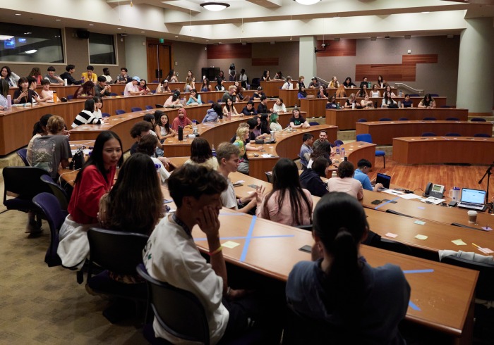 A large group of students sit in a lecture hall