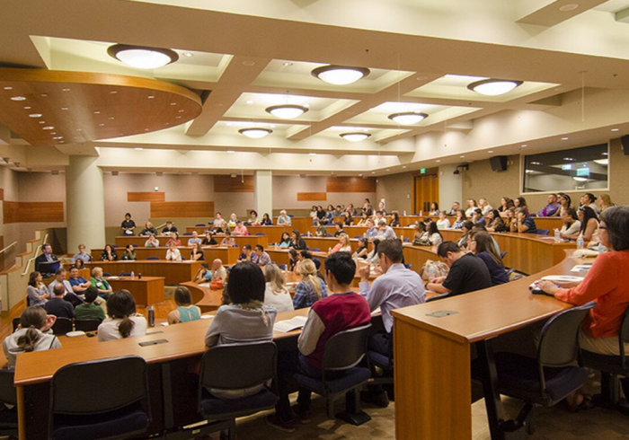 A large group of people sit in an auditorium.