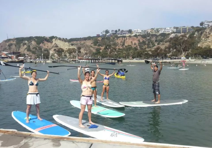 Students show off their paddles while paddleboarding during an outdoor adventure series.