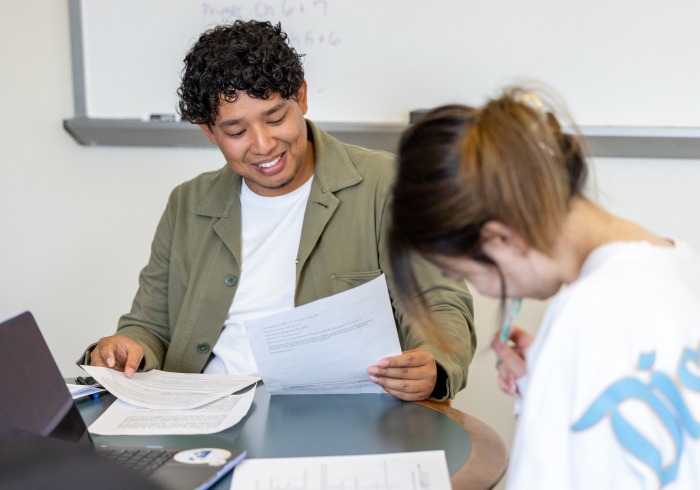 A student smiles while reviewing handouts during class.