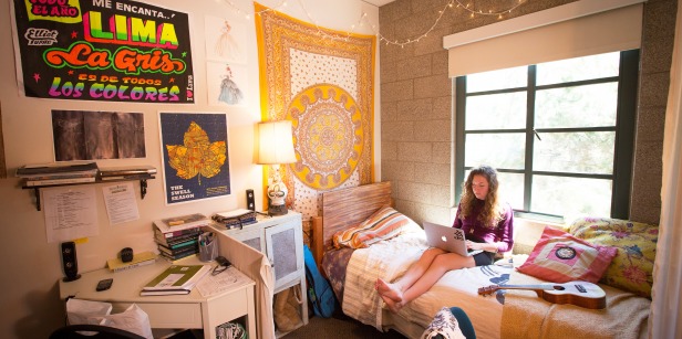 Girl sitting on bed in residence hall dorm room