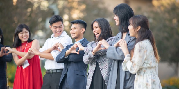 Student group making heart shaped hand signals