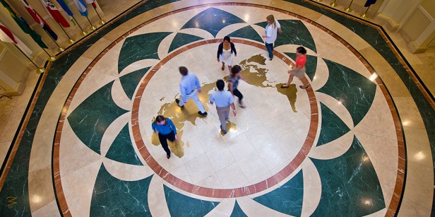 Students mingle on map of globe on the floor of Founders Hall