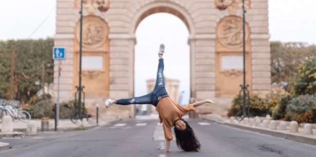 student doing cartwheel in front of arch