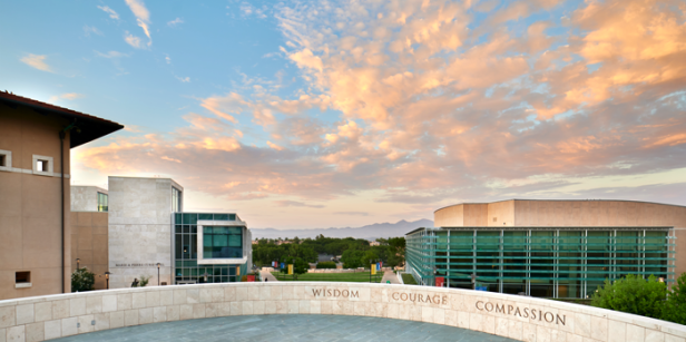 The three central values of Soka University, Wisdom, Courage, & Compassion, are displayed on a wall in front of clouds and silhouetted mountains as the backdrop