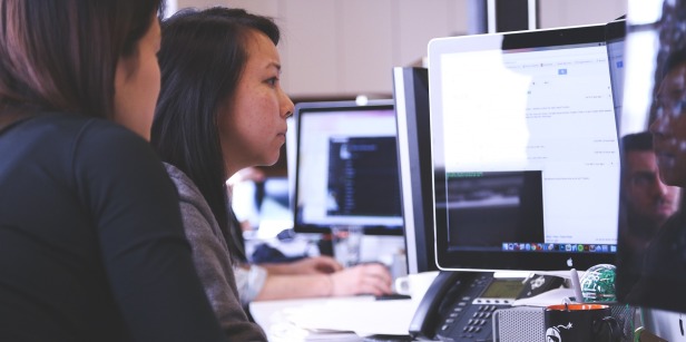 Two women work on a computer together