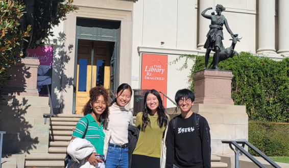 Four students pose outside the Huntington Library during a field trip.