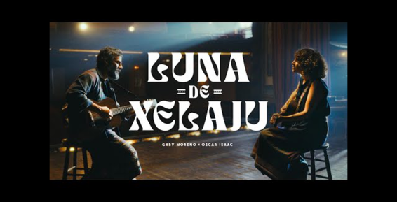 Screengrab of Oscar Isaac and Gaby Moreno playing guitar and singing on stage during the filming of the music video for the song "Luna de Xelajú"