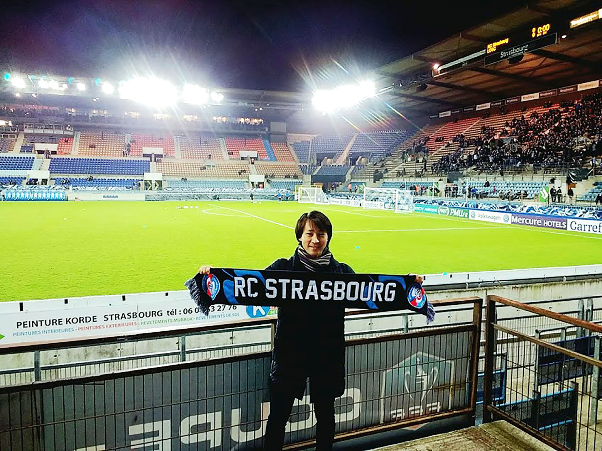 Student in front of football green with Strasbourg banner