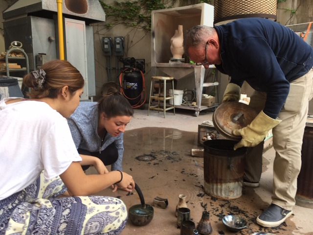 Image of students working with the ceramics instructor.