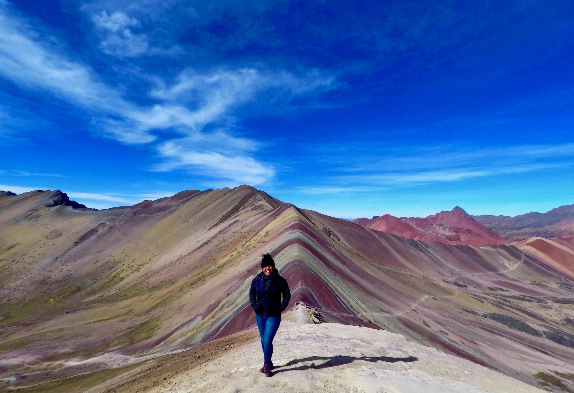 Delali standing in front of Spring Rainbow Mountain in Ecuador