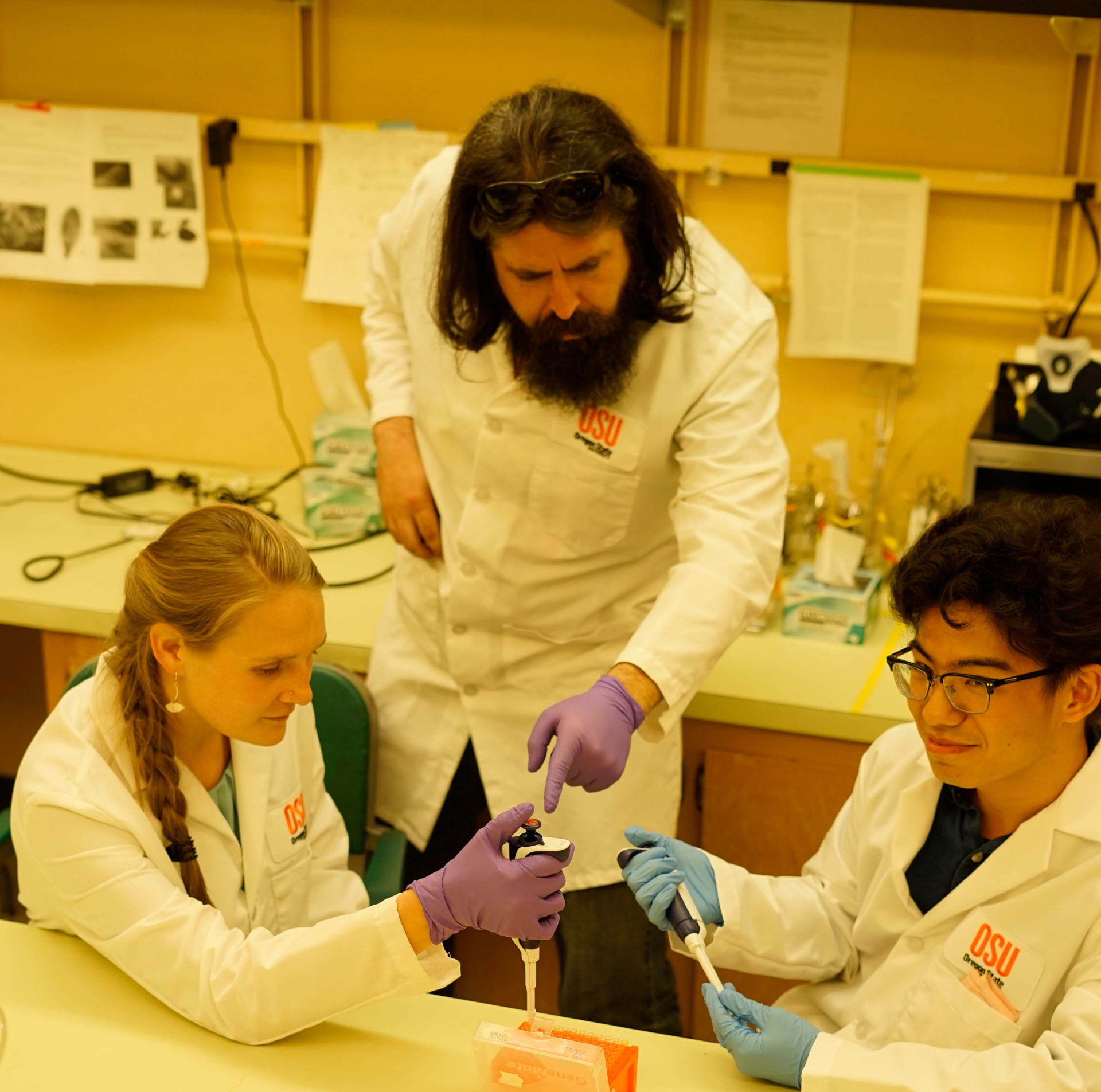 Two students with a professor in a lab. 