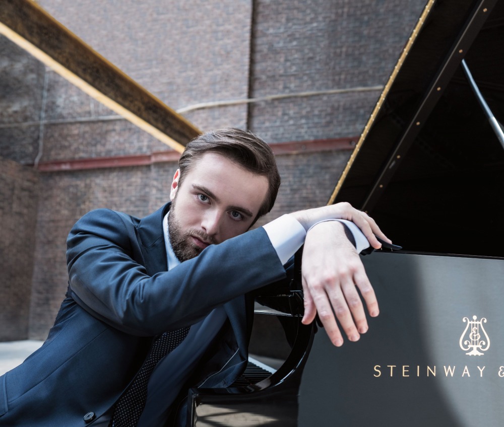 Daniil Trifonov sitting with hand on piano