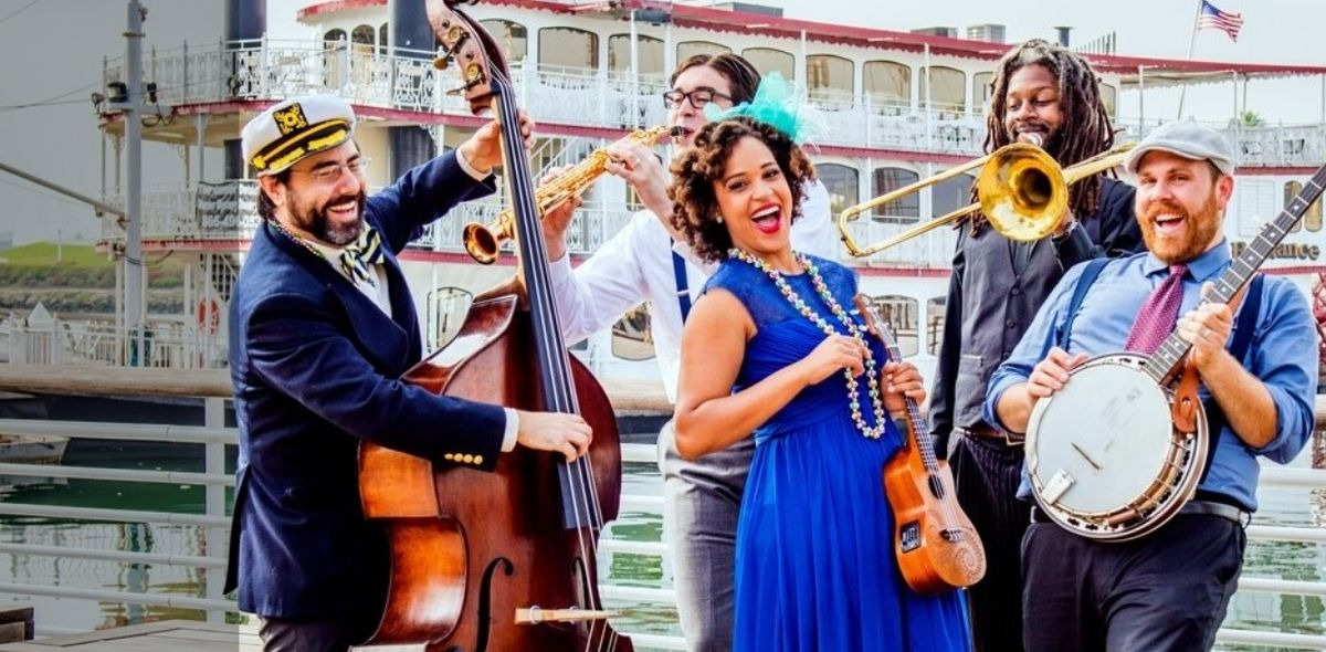 Jazzy Ash and band members playing instruments on a dock