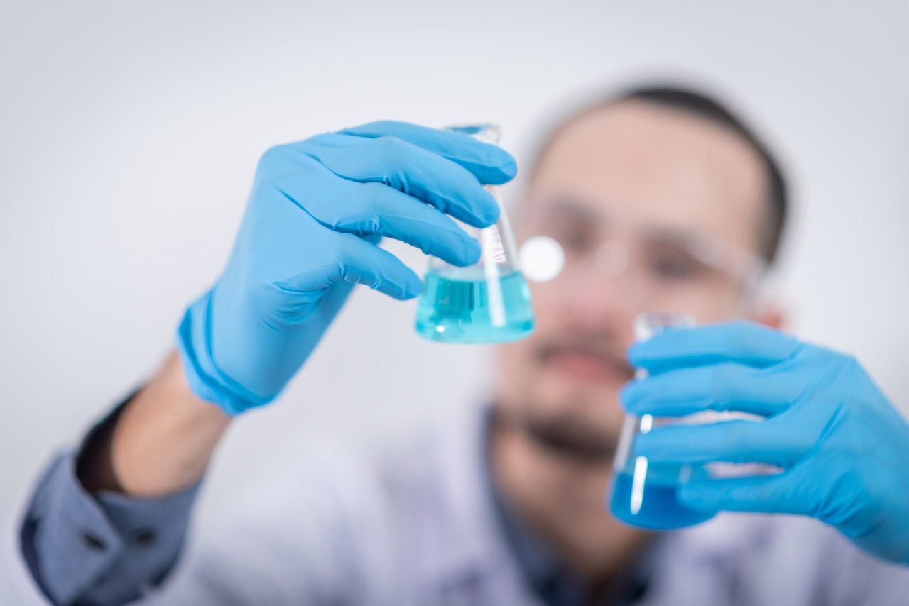 Person holding glass flasks in a lab