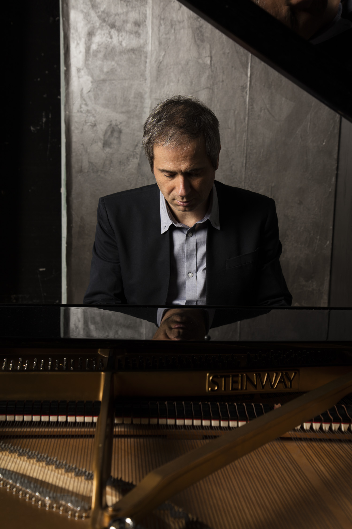Piotr Anderszewski sitting at piano looking down