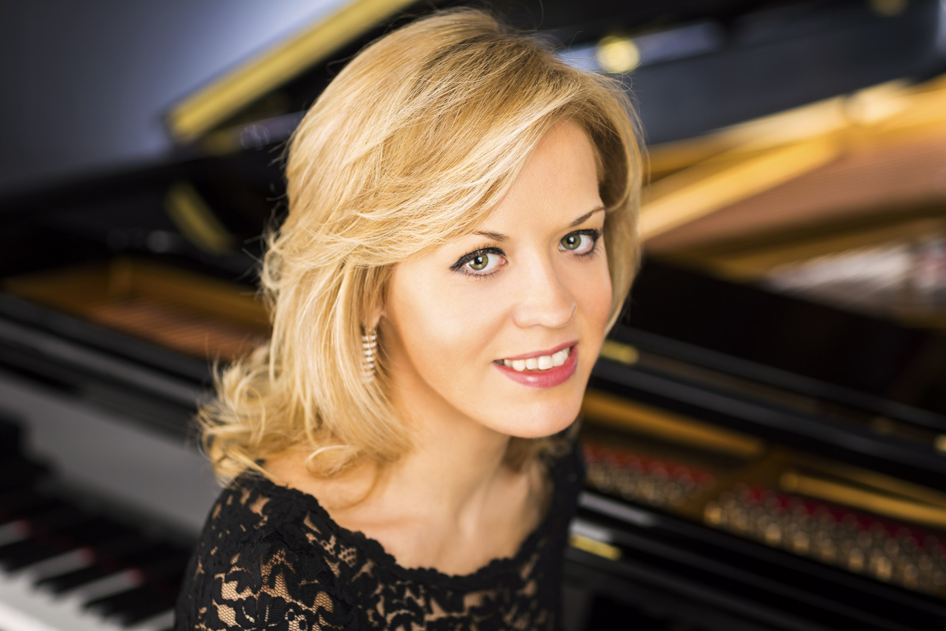 Olga Kern sitting at a piano wearing a black dress