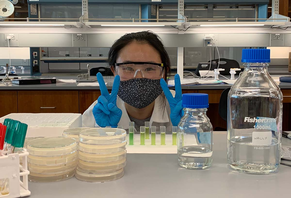 Woman flashing peace sign in bio lab