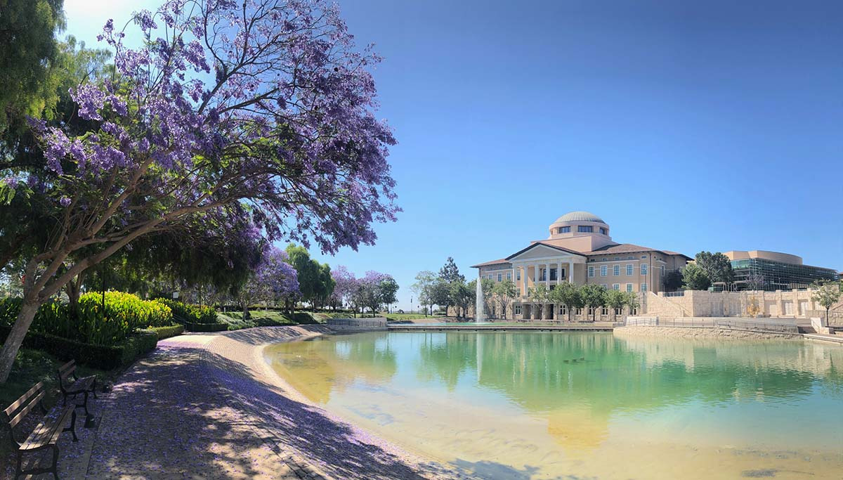 Peace Lake bounded by purple trees with Founders Hall in the background