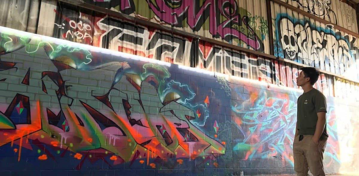 Soka University student looking up at wall of graffiti